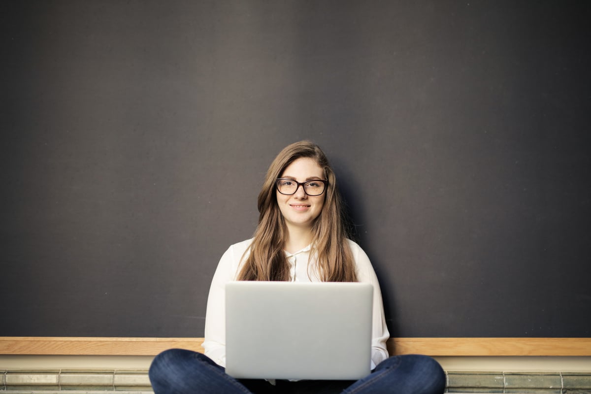 Woman Smiling While Using a Laptop